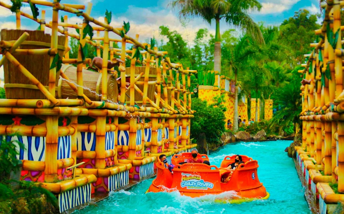 Raft on Crazy River ride at Beto Carrero World, surrounded by bamboo structures and lush greenery.