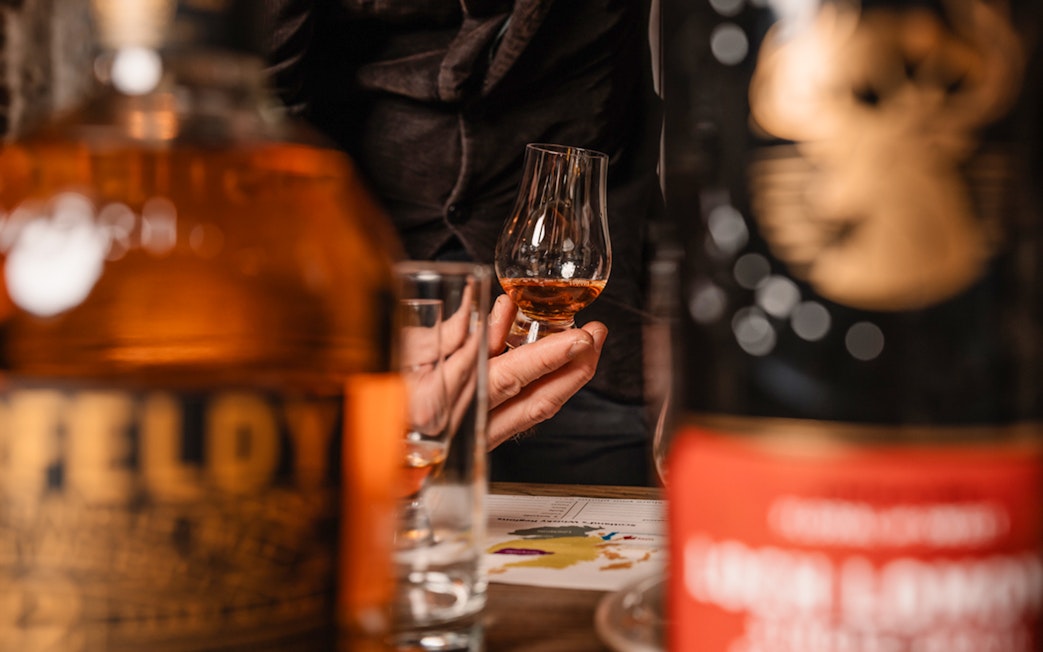 Hand holding whisky glass during tasting on Edinburgh underground tour.