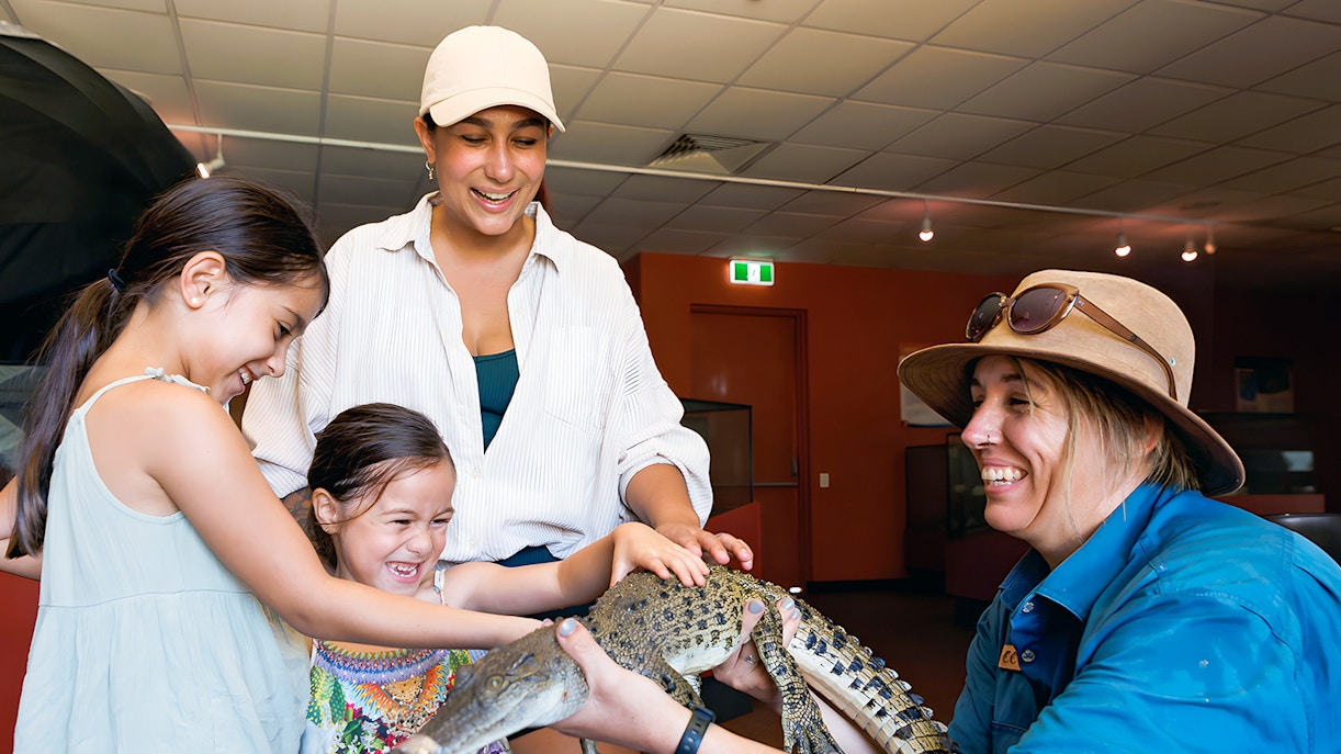 Guests at Crocosaurus Cove petting a baby crocodile