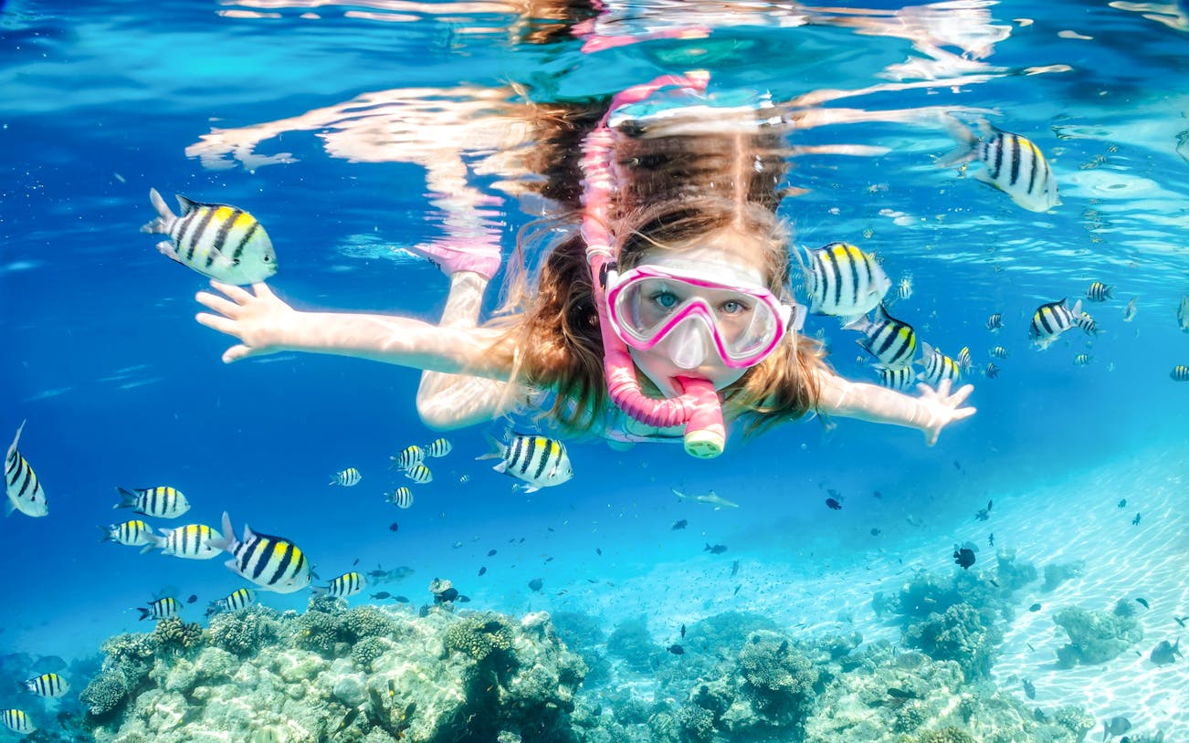 Little girl snorkeling in clear waters at White Island, Sharm El-Sheikh, Egypt.