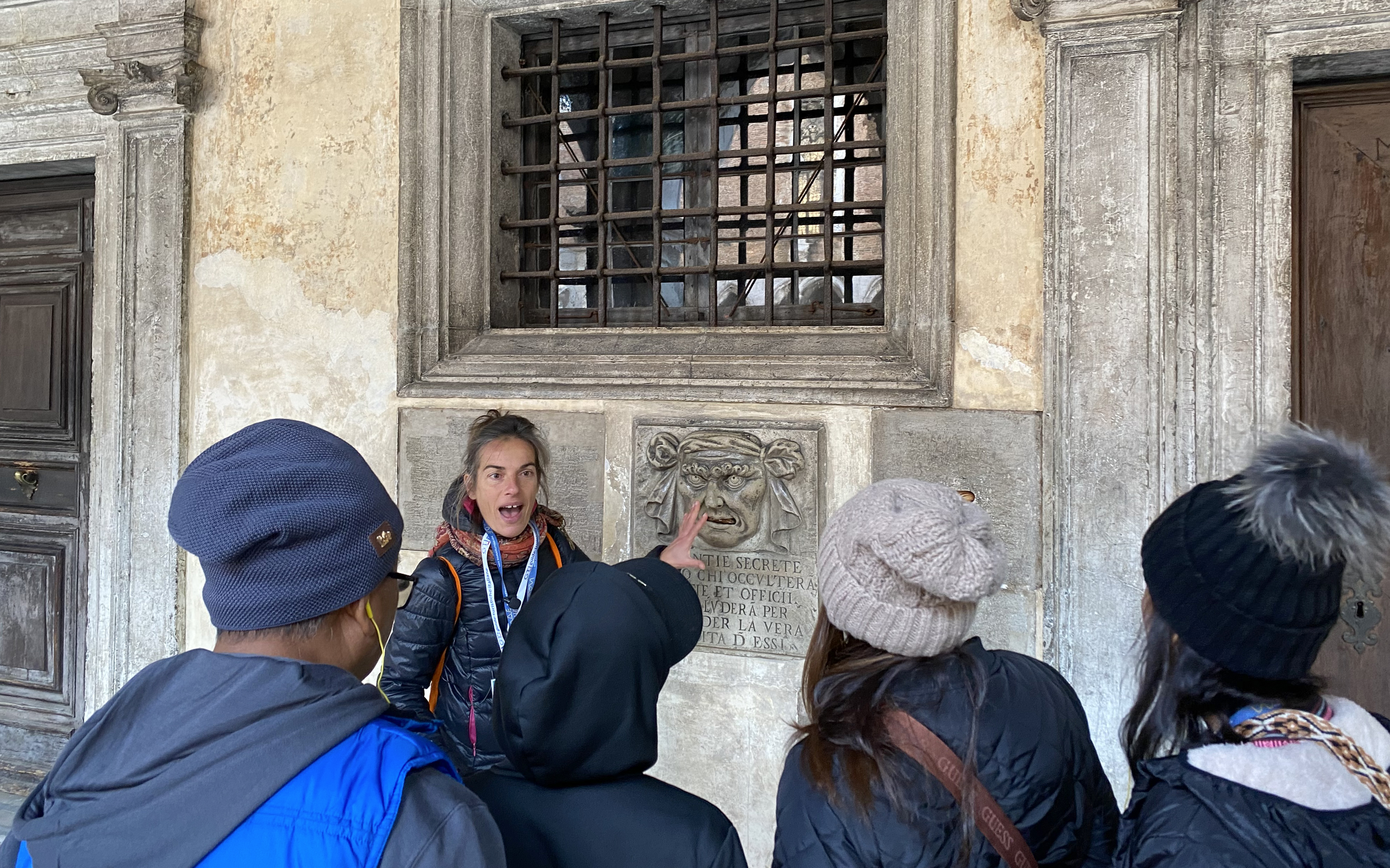 Guide explaining a historical feature to tourists at Doge's Palace, Venice.
