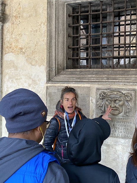 Guide explaining a historical feature to tourists at Doge's Palace, Venice.