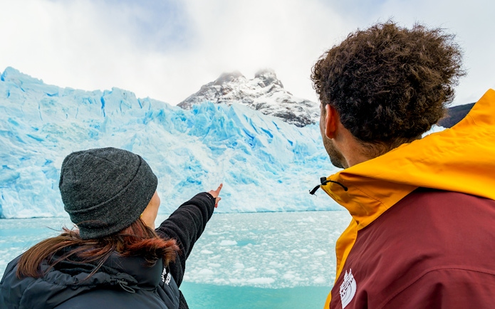 Tourists on a boat pointing at Perito Moreno Glacier in Argentina.