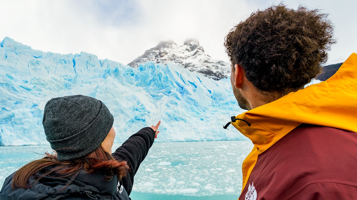 Tourists on a boat pointing at Perito Moreno Glacier in Argentina.