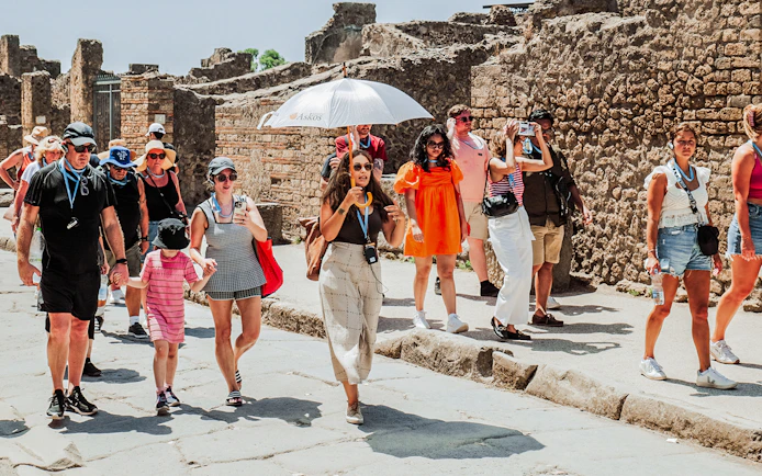 Tour group exploring ancient ruins in Pompeii with a guide.