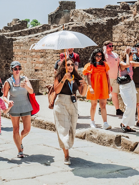 Tour group exploring ancient ruins in Pompeii with a guide.