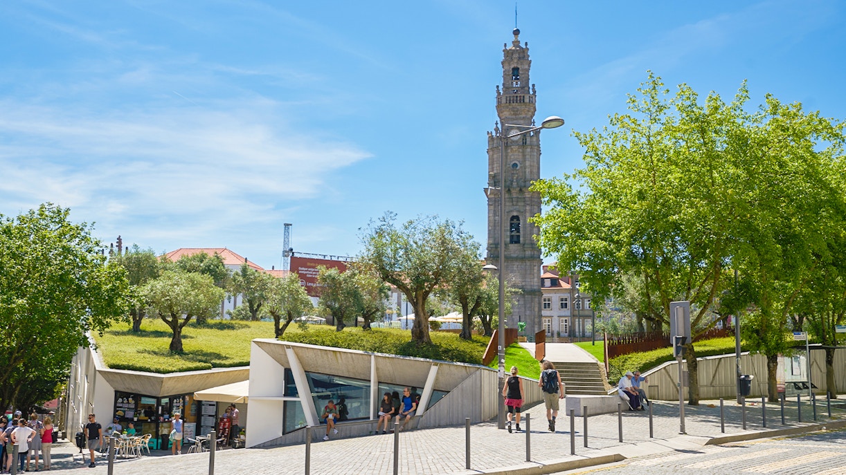 Clérigos Tower in Porto with surrounding park and visitors walking nearby.