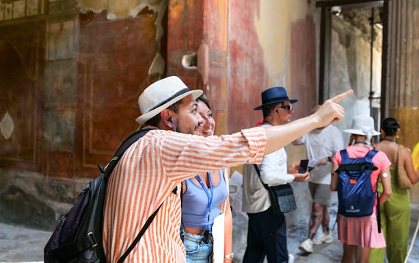 Tourists exploring ancient frescoes at Pompeii ruins.