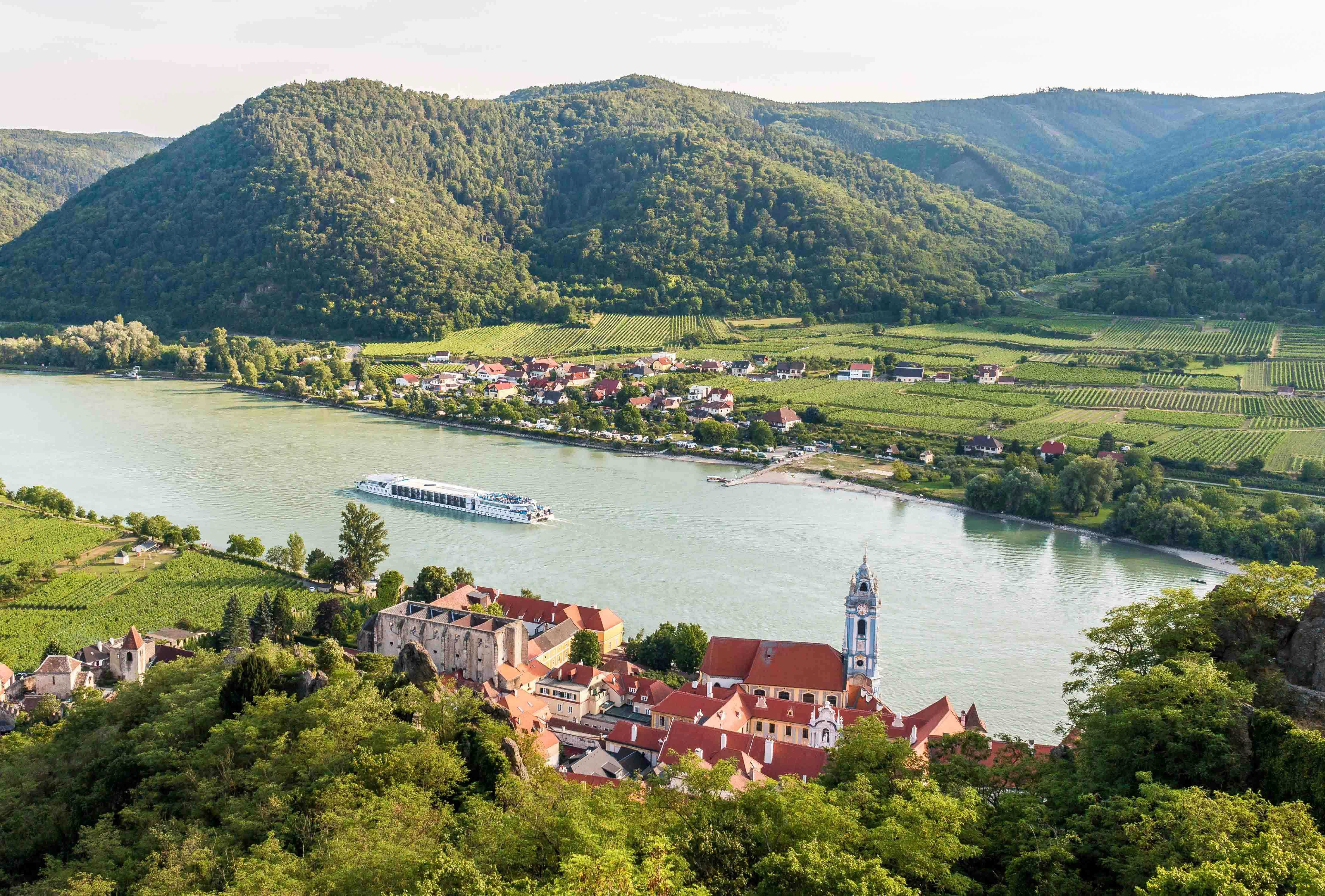 Cruise ship on the Danube River near Dürnstein, Austria, with vineyards and hills in the background.