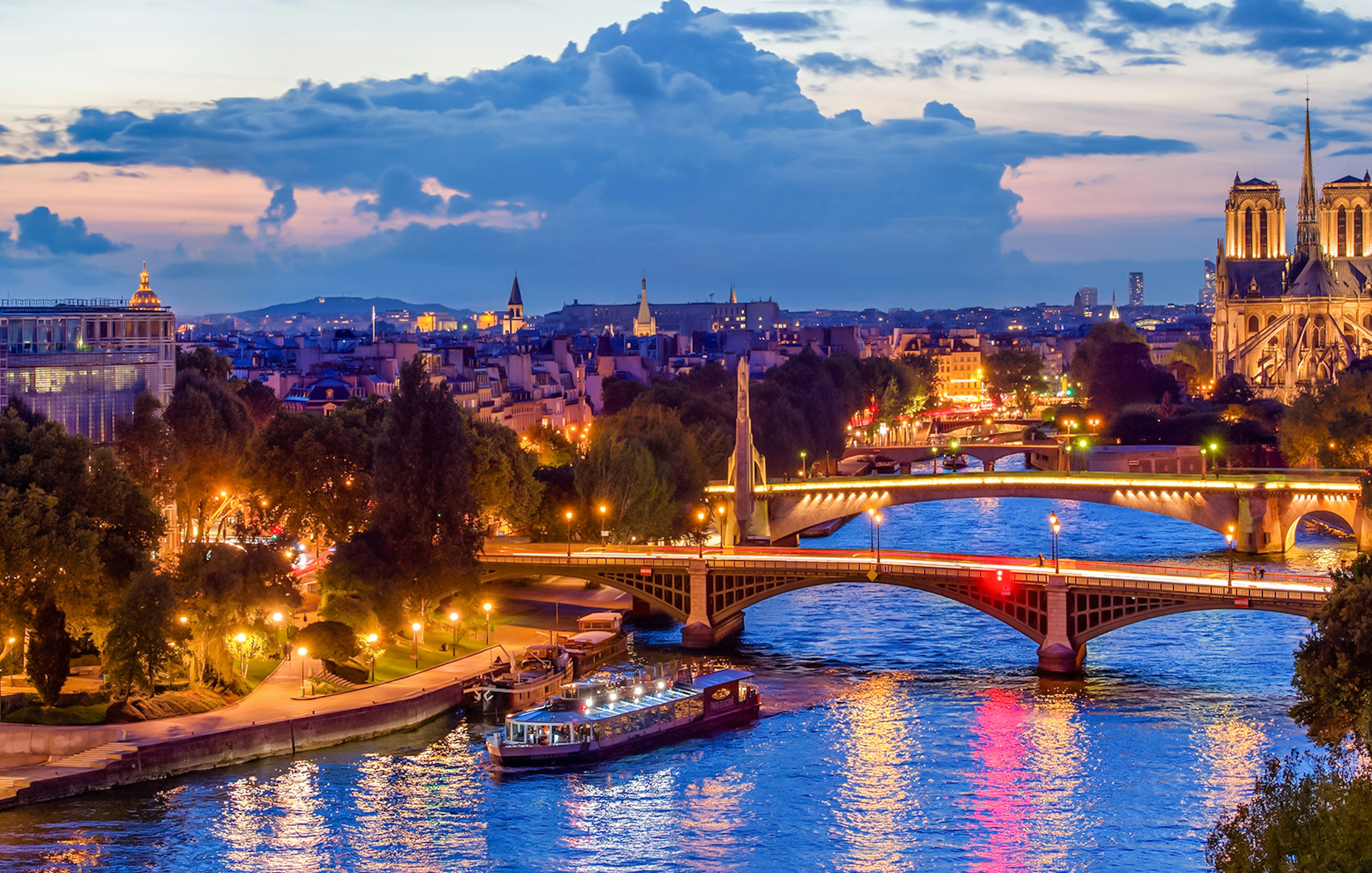 Paris skyline at night with Seine river and Paris En Scène Dinner Cruise boat.