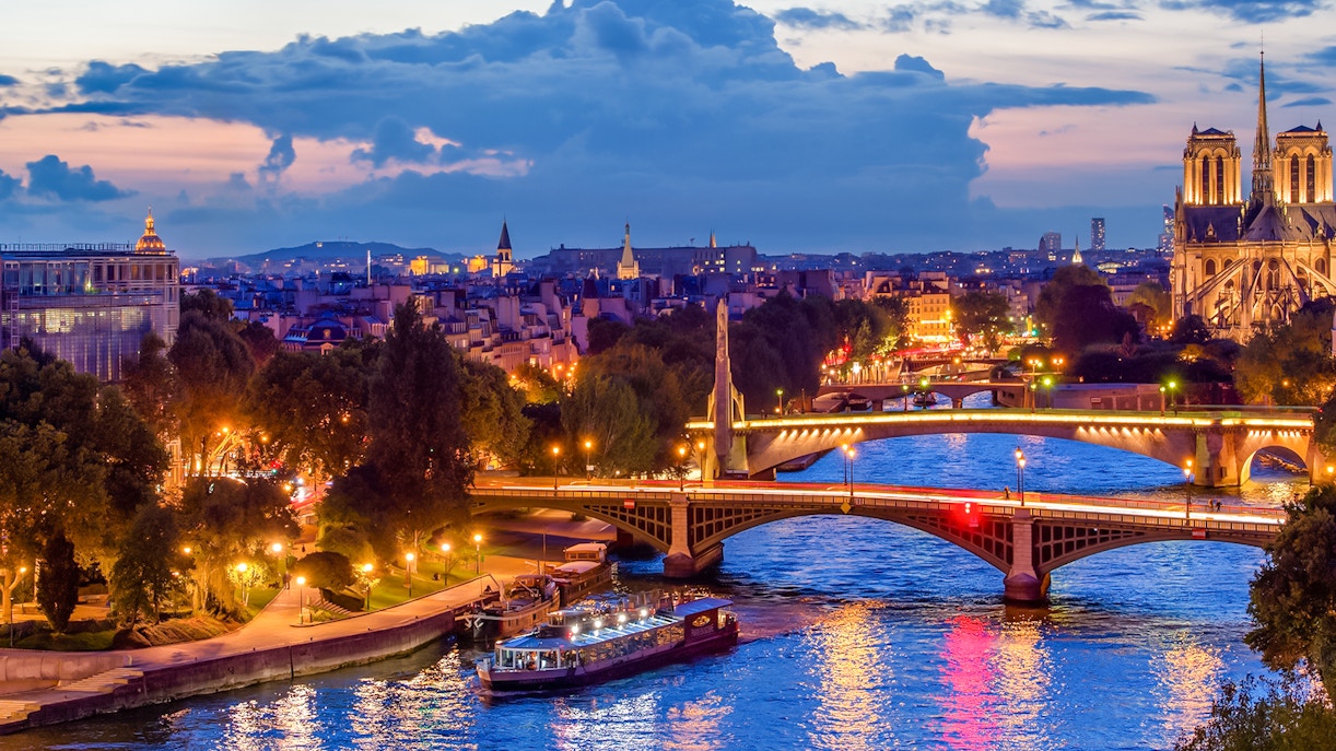 Paris skyline at night with Seine river and Paris En Scène Dinner Cruise boat.
