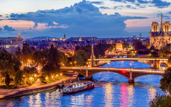 Paris skyline at night with Seine river and Paris En Scène Dinner Cruise boat.