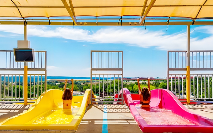 Children on colorful water slides at Aquopolis Villanueva de la Cañada, Madrid.