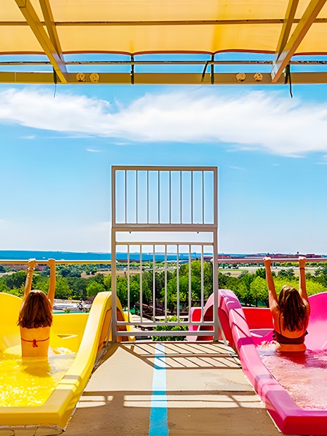 Children on colorful water slides at Aquopolis Villanueva de la Cañada, Madrid.