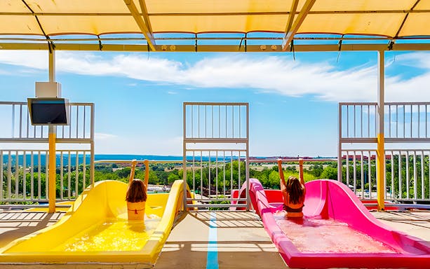 Children on colorful water slides at Aquopolis Villanueva de la Cañada, Madrid.