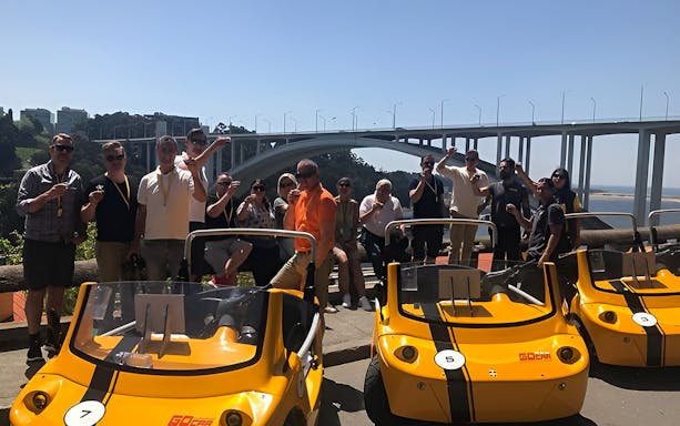 Group enjoying a Porto GoCar tour with Arrábida Bridge in the background.
