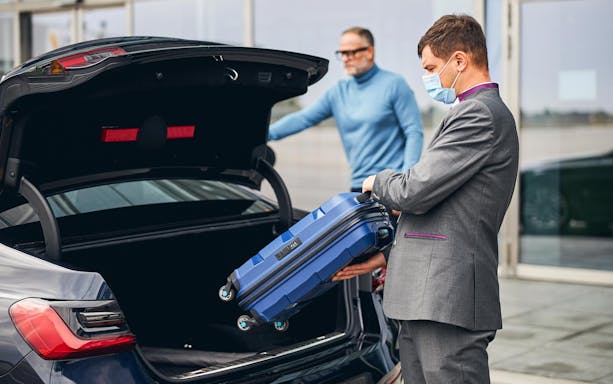 Man loading suitcase into car trunk at Katowice Pyrzowice airport transfer.