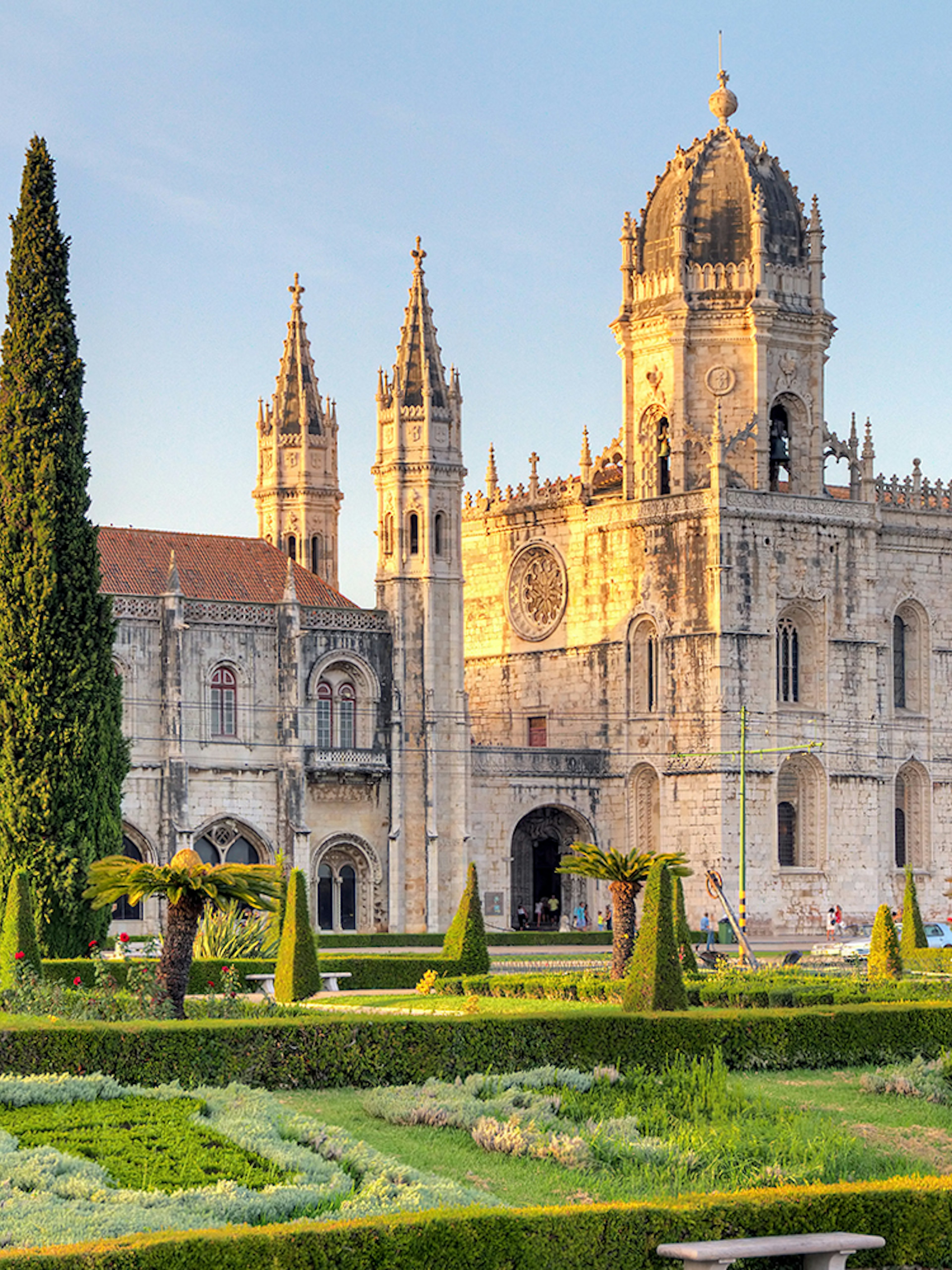 Jeronimos Monastery in Lisbon with manicured gardens in the foreground.