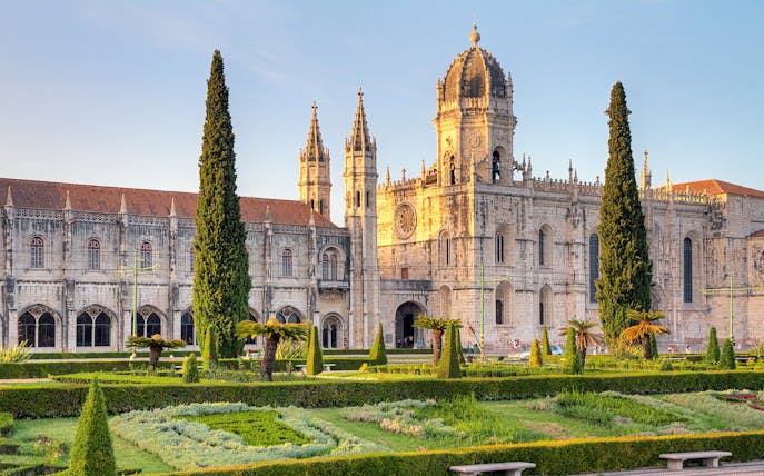Jeronimos Monastery in Lisbon with manicured gardens in the foreground.