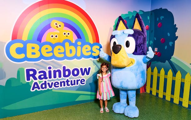 CBeebies Rainbow Adventure sign with character mascot and child smiling.