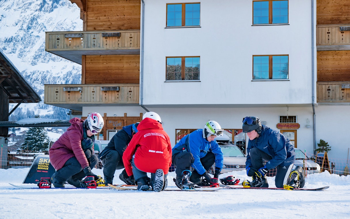 Beginners preparing snowboards in Grindelwald during full-day package from Interlaken.