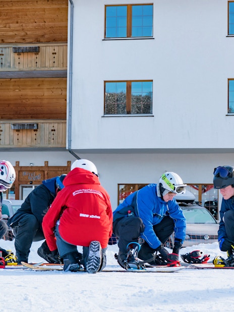 Beginners preparing snowboards in Grindelwald during full-day package from Interlaken.