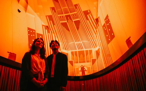 Visitors enjoying a guided tour inside the Sydney Opera House with vibrant lighting display.