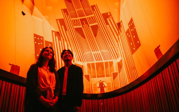 Visitors enjoying a guided tour inside the Sydney Opera House with vibrant lighting display.
