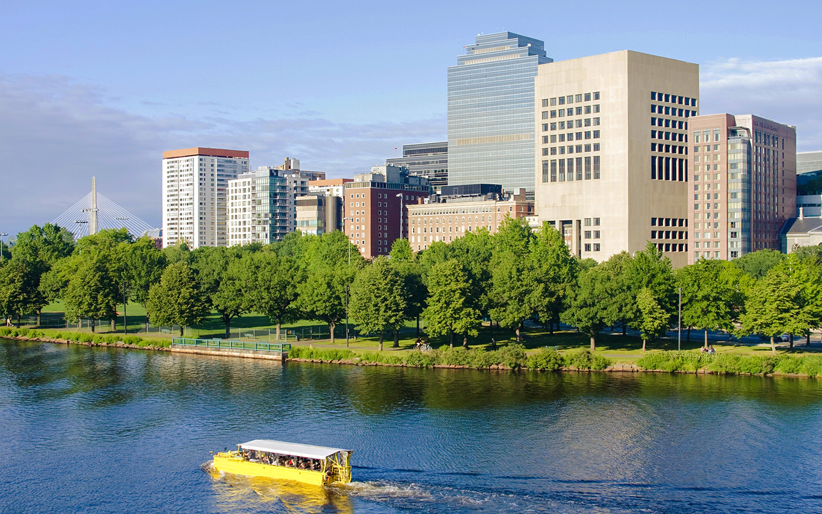Yellow amphibious vehicle on Charles River with Boston skyline in background.