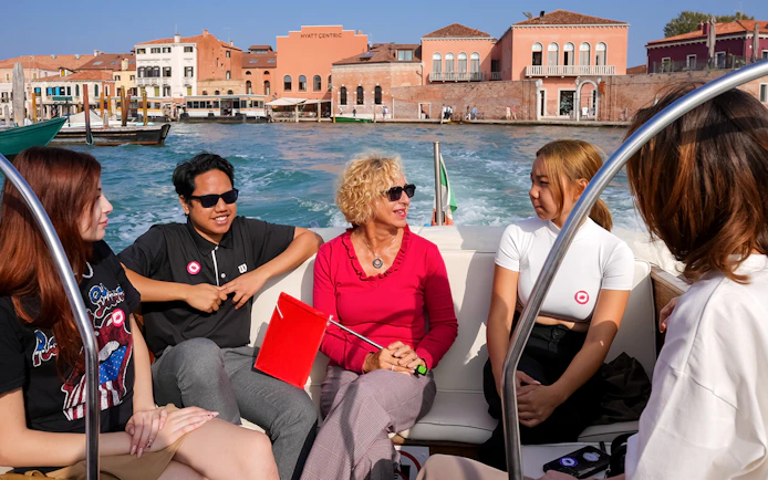 Tourists enjoying a boat ride in Venice with historic buildings in the background.