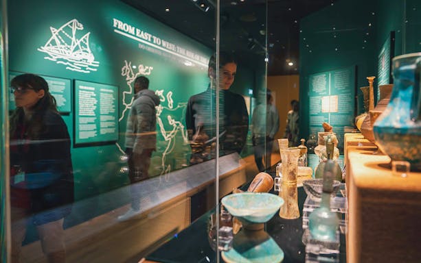 Visitors viewing ancient artifacts at The Bridge Collection exhibit.