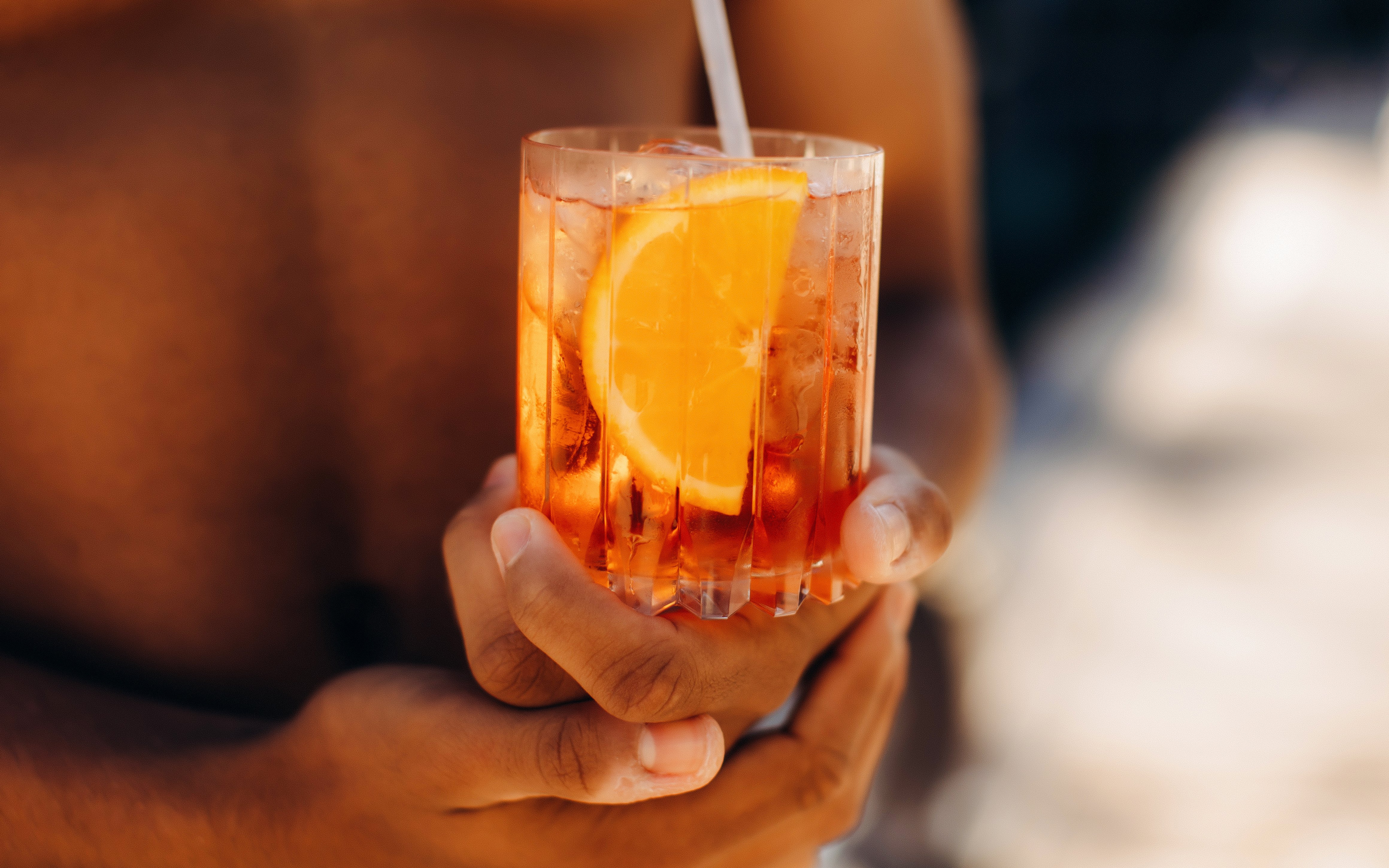 Man holding an Aperol Spritz cocktail with an orange slice.