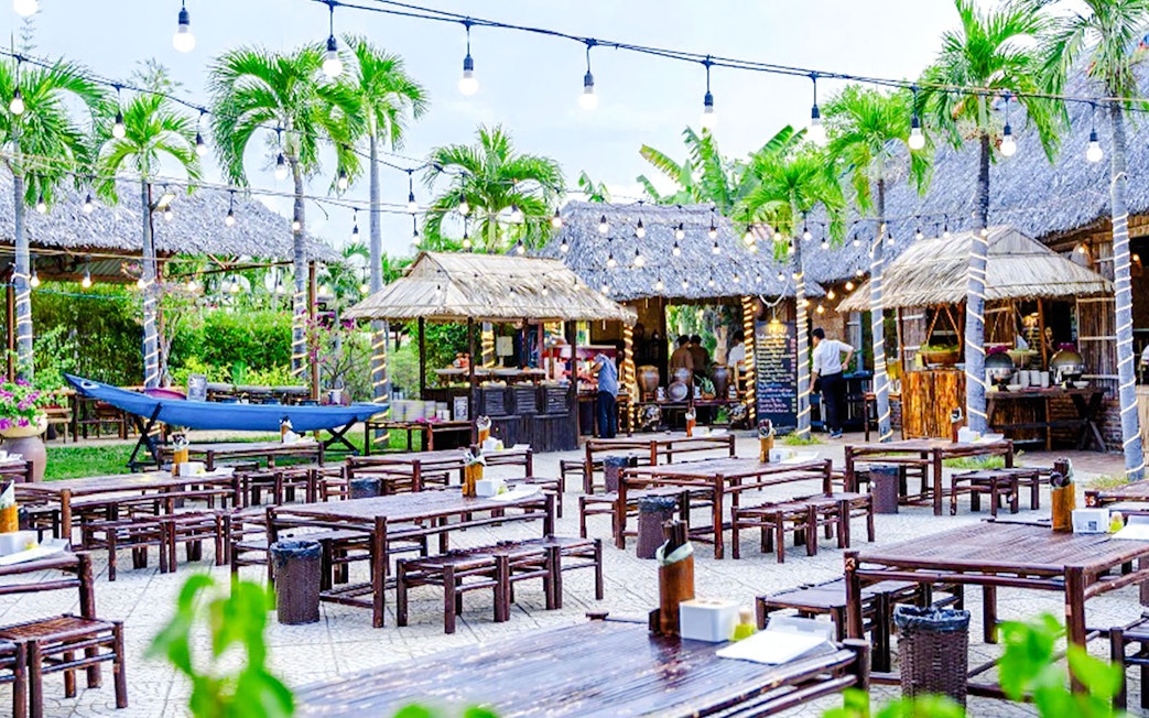 Outdoor dining area with wooden tables and thatched roofs in Hoi An, Vietnam.