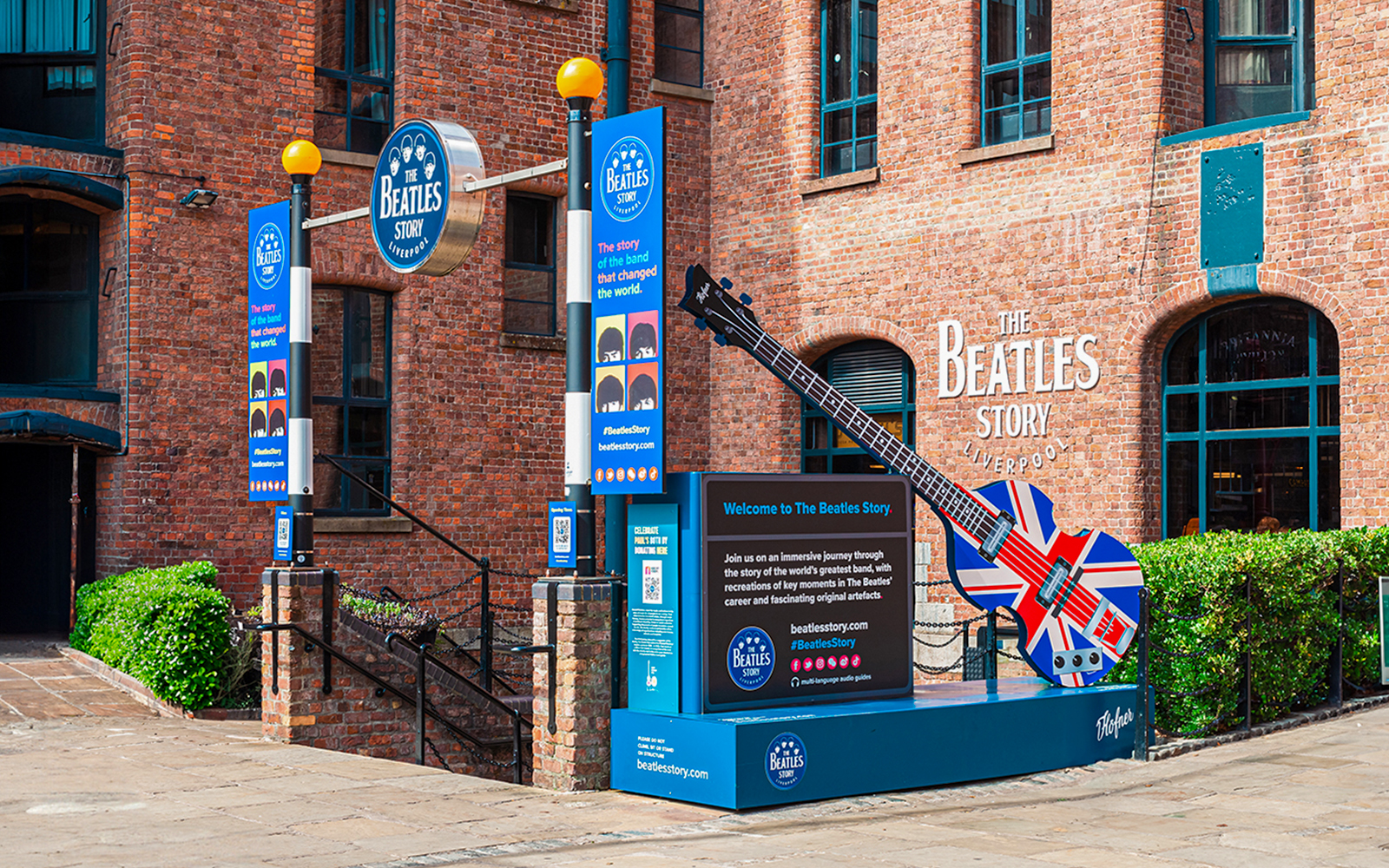 Exteriors of The Beatles Story museum in Liverpool with signage and Union Jack guitar display.
