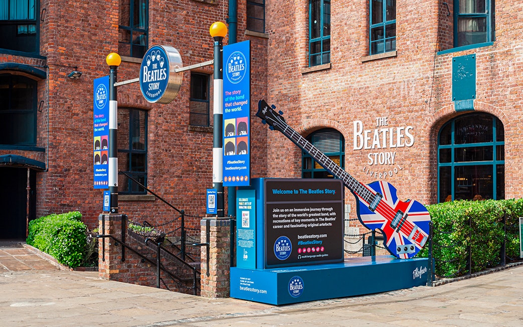 Exteriors of The Beatles Story museum in Liverpool with signage and Union Jack guitar display.