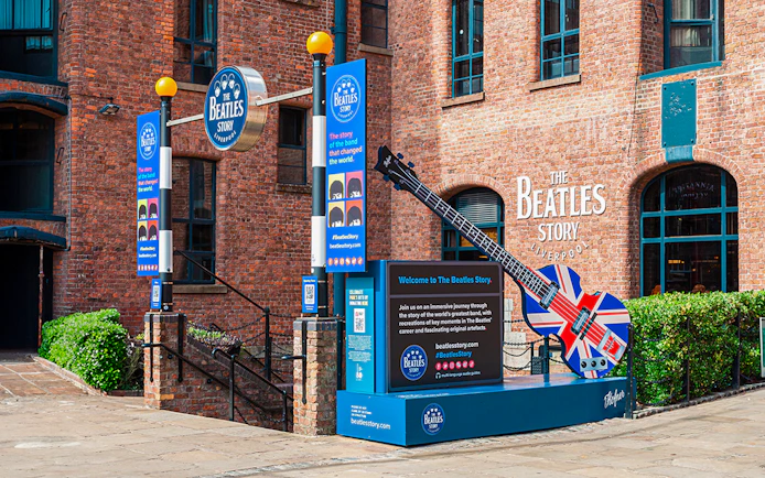 Exteriors of The Beatles Story museum in Liverpool with signage and Union Jack guitar display.