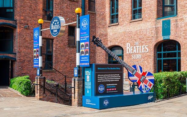 Exteriors of The Beatles Story museum in Liverpool with signage and Union Jack guitar display.