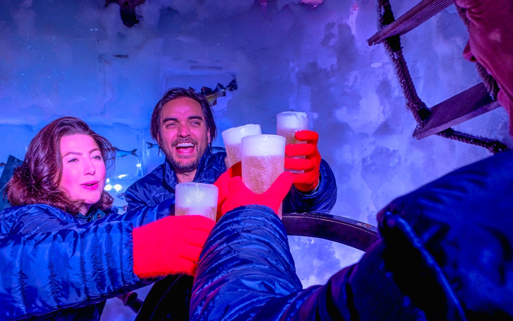 Guests enjoying drinks at Icebar Amsterdam with ice walls and vibrant lighting.