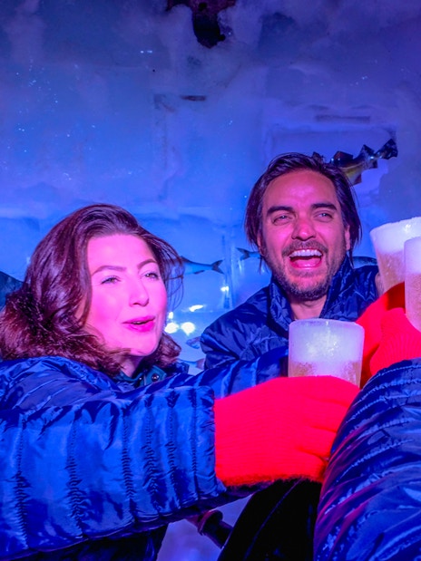 Guests enjoying drinks at Icebar Amsterdam with ice walls and vibrant lighting.