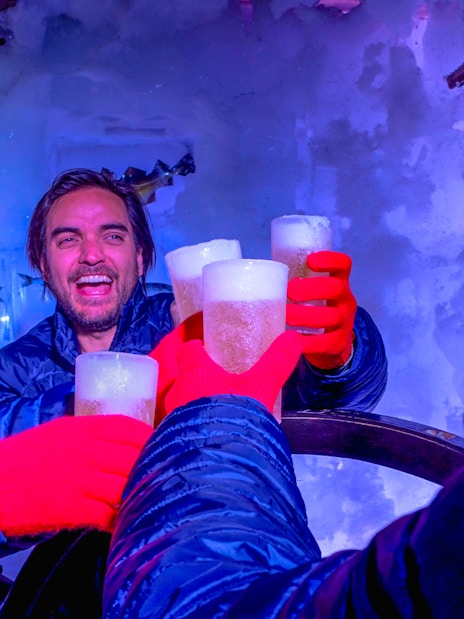 Guests enjoying drinks at Icebar Amsterdam with ice walls and vibrant lighting.