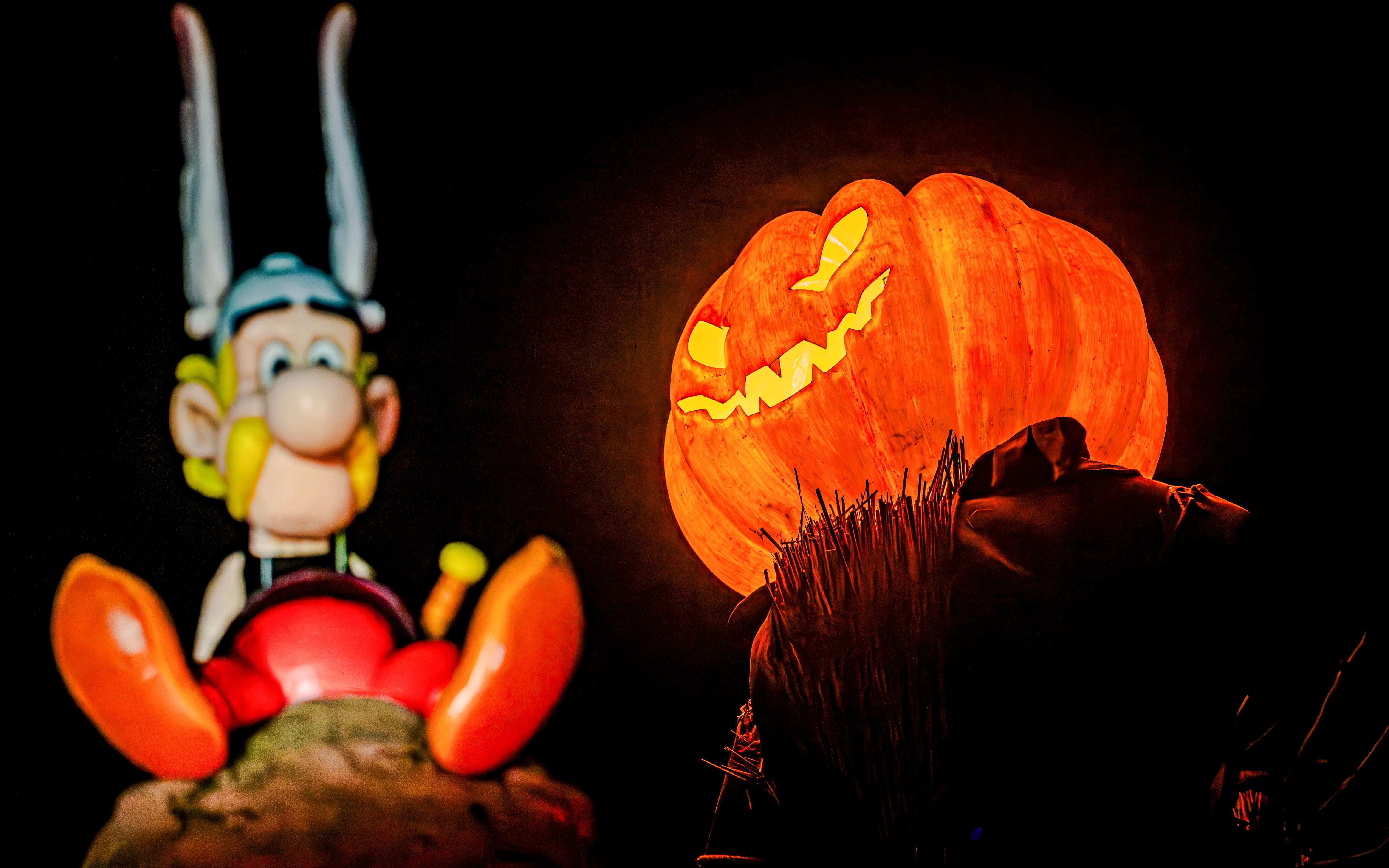 Asterix statue and glowing jack-o'-lantern at Parc Asterix Halloween event in Paris, France.