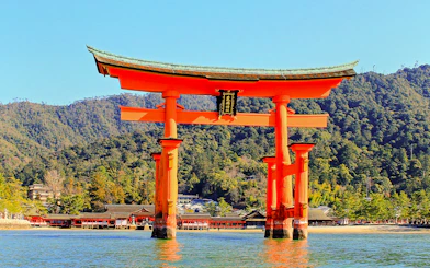 Otorii Gate at Itsukushima Shrine, Miyajima Island, Japan, with forested hills in the background.