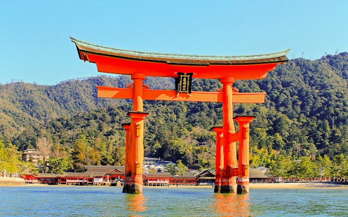 Otorii Gate at Itsukushima Shrine, Miyajima Island, Japan, with forested hills in the background.