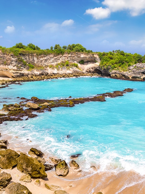 Blue Lagoon at Nusa Ceningan, Bali, with turquoise waters and rocky cliffs.