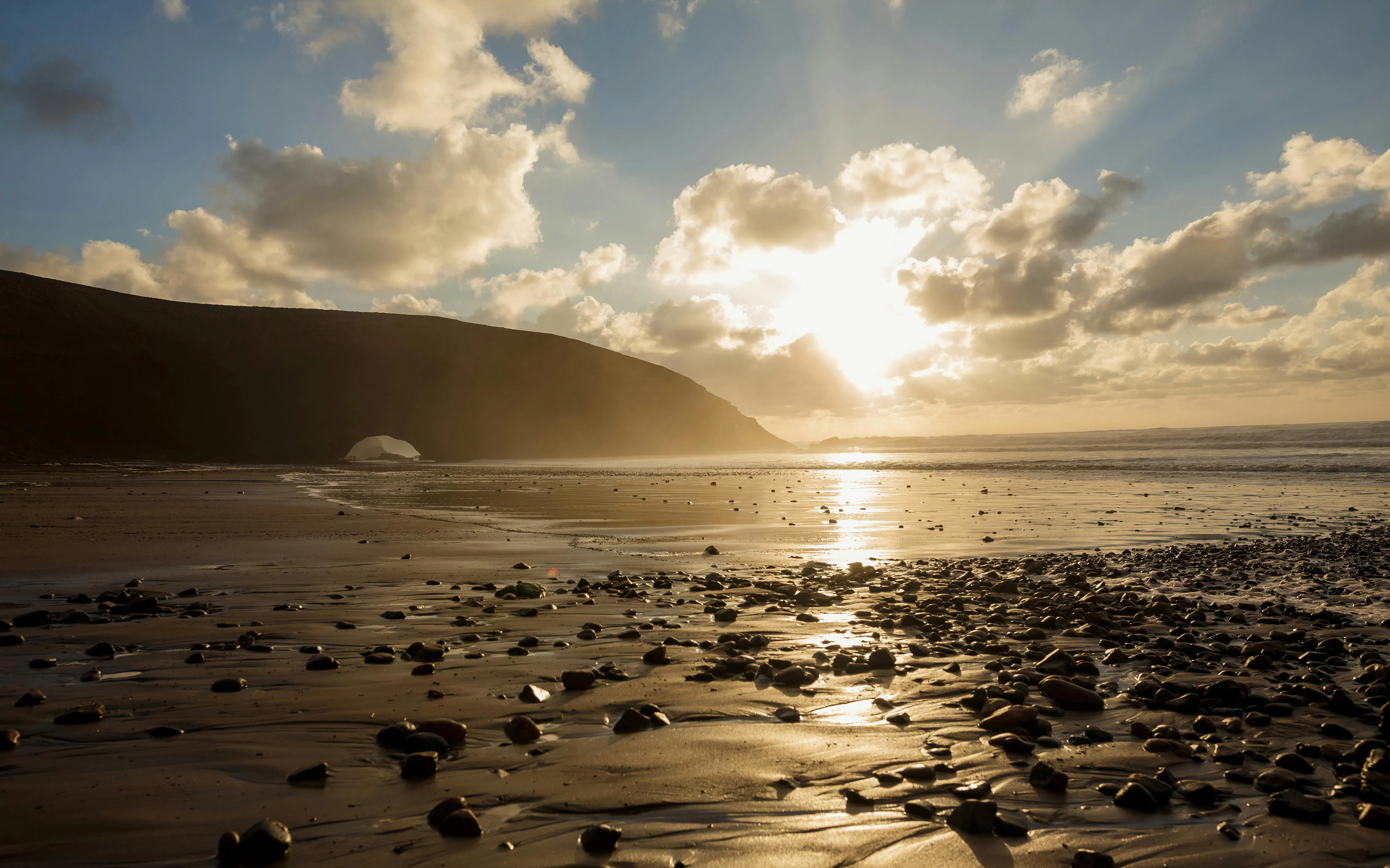 Sunset over rocky shoreline at Legzira Beach, Morocco.