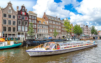 Canal cruise boat on Amsterdam canal with historic buildings in the background.