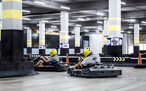 Indoor go-karting track with racers in Bangkok.