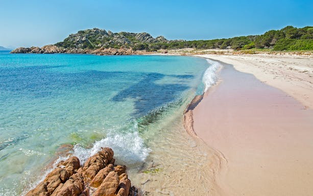 La Maddalena Archipelago beach with clear turquoise water and rocky shoreline.