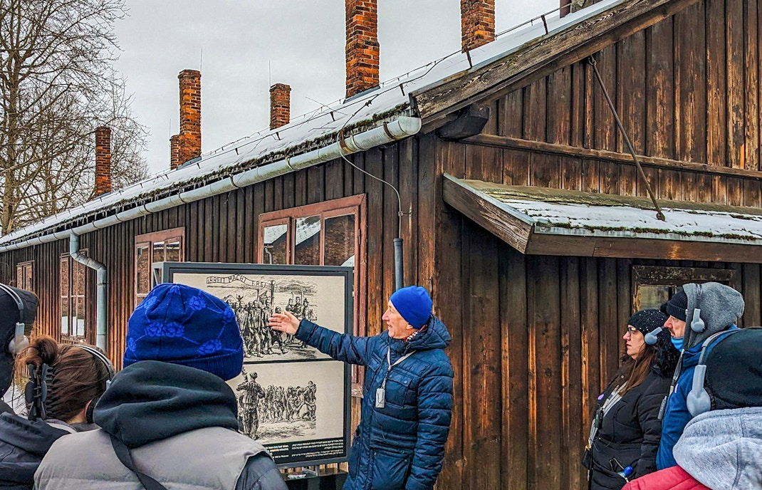 Auschwitz Birkenau guided tour visitors walking through Auschwitz I entrance gate.