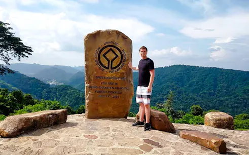 Man standing by Dong Phayayen-Khao Yai Forest Complex sign, Khao Yai National Park.